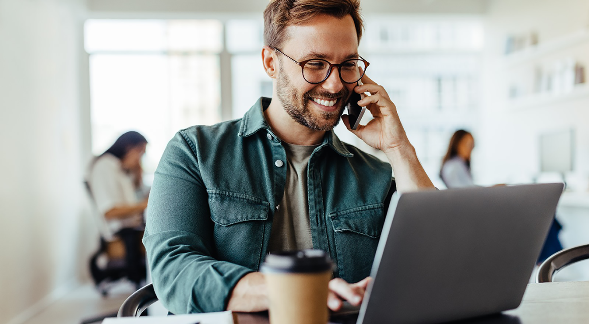 a man talking on a cell phone while looking at a laptop